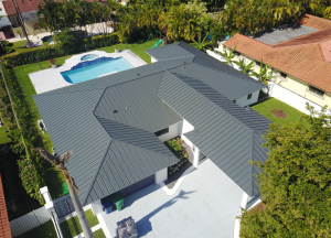 Aerial view of a standing seam metal roof on a Florida residential home showing hip geometry and multiple roof planes. 